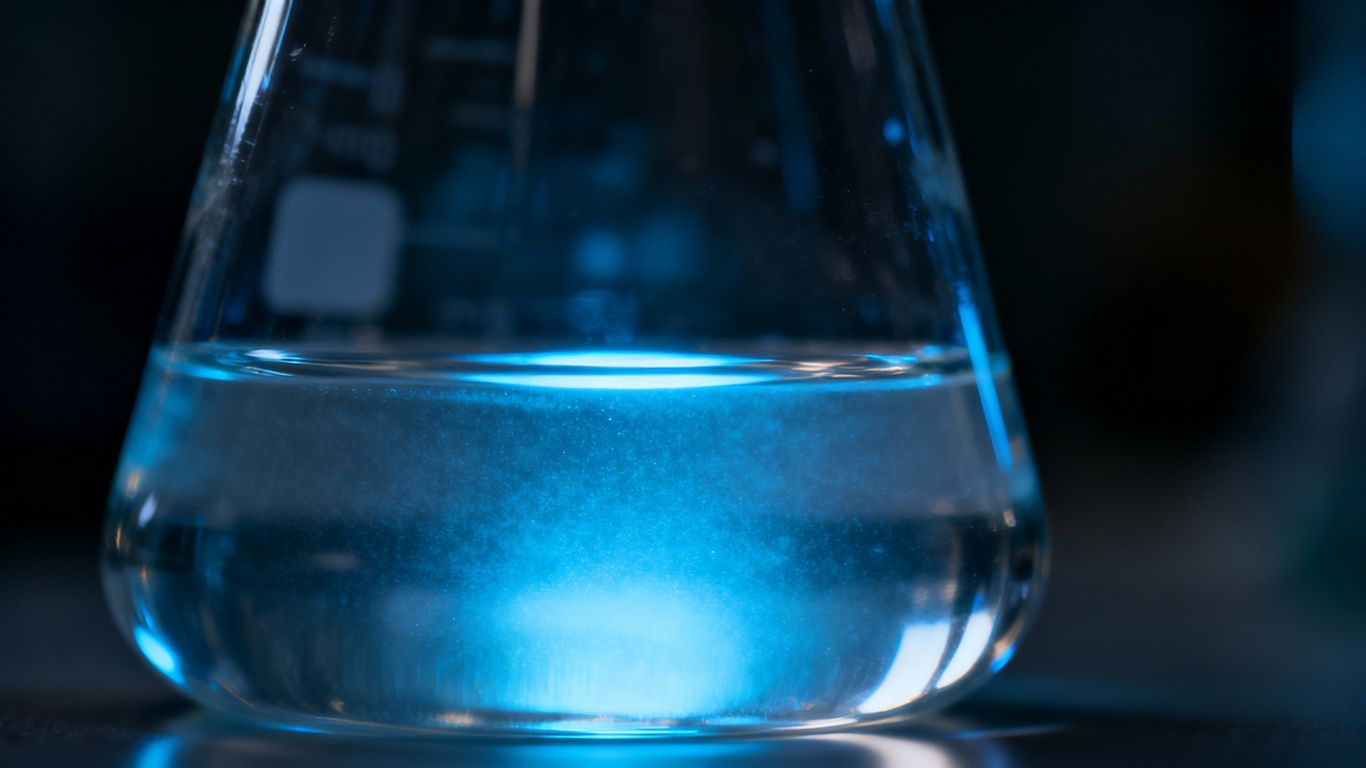 Laboratory beaker with glowing blue liquid.